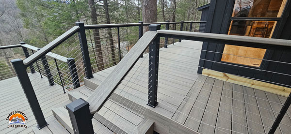 Image of a home in the forest with a cable railing deck.